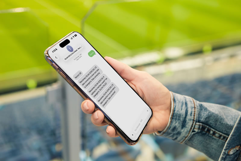 Hand hält ein Smartphone in einem Sportstadion und sendet Textnachrichten an IOLAN SCRC, um eine Mobilfunkverbindung zu ermöglichen
